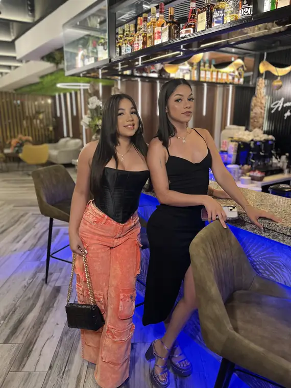 Amigas posando en la barra iluminada