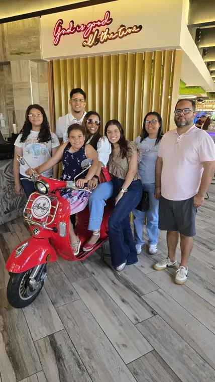 Familia en la Vespa bajo el letrero de neón