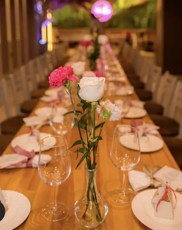 Mesa larga de evento con claveles y rosas
