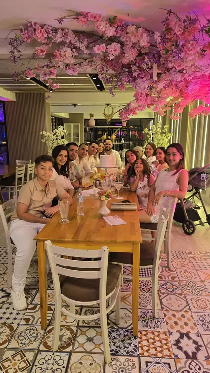Familia reunida en una mesa larga bajo flores de cerezo