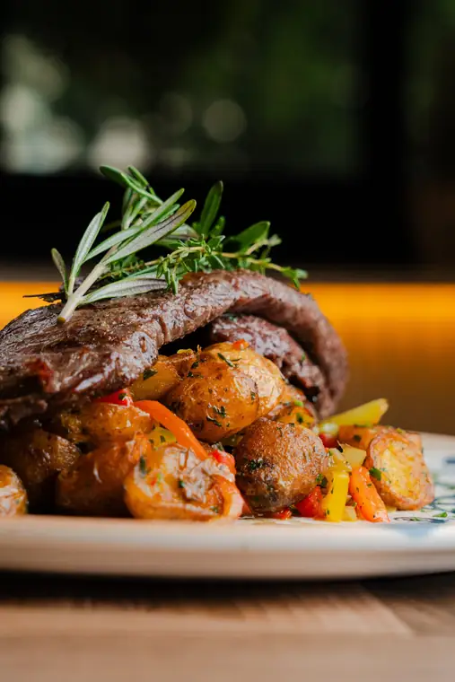 Churrasco Angus a la parrilla sobre papitas y pimientos